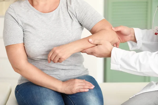 Doctor examining mature woman with joint pain in clinic — Stock Photo, Image