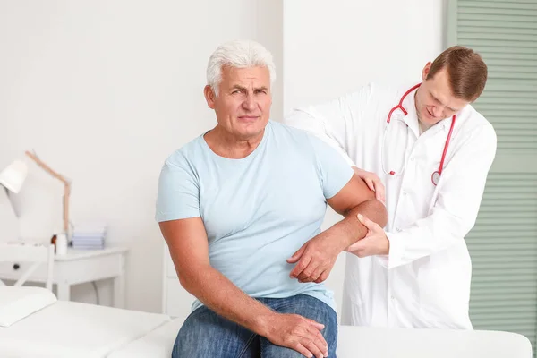 Doctor examining mature man with joint pain in clinic — Stock Photo, Image