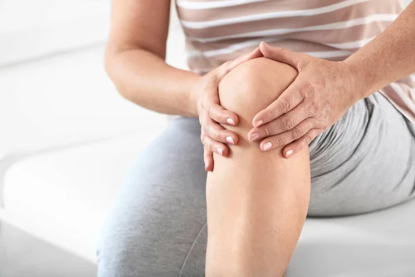 Dojrzała kobieta cierpiąca na ból kolana w klinice, zbliżenie — Zdjęcie stockowe