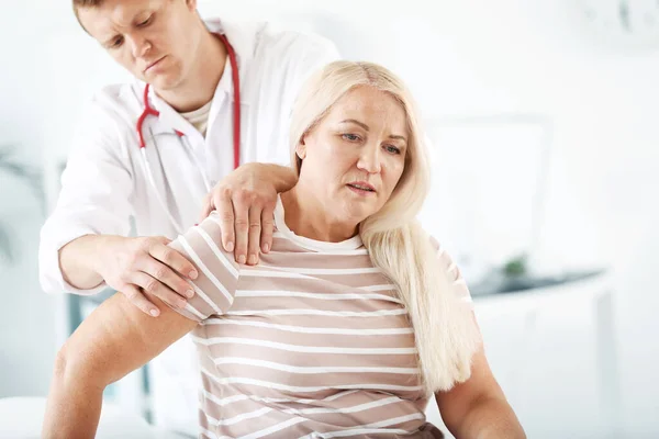 Klinikte eklem ağrısı olan olgun bir kadını muayene eden doktor. — Stok fotoğraf