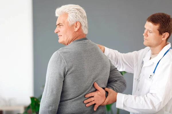 Dokter onderzoeken volwassen man met gewrichtspijn thuis — Stockfoto