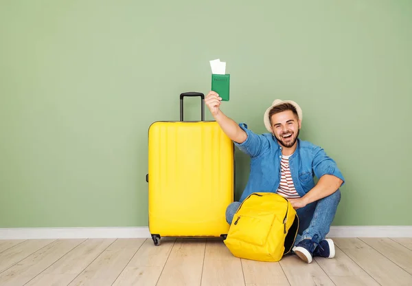 Young male tourist with luggage sitting near color wall — Stock Photo, Image