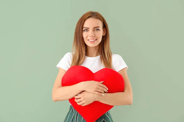 Beautiful young woman with big red heart on color background — Stock Photo, Image