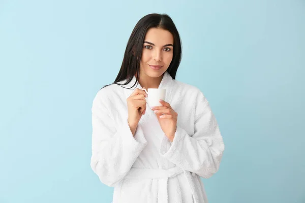Beautiful young woman after shower drinking coffee on color background — Stock Photo, Image