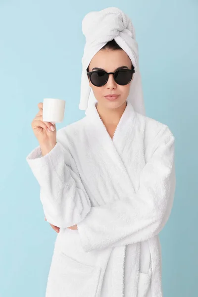 Beautiful young woman after shower drinking coffee on color background — Stockfoto