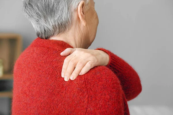 Starší žena trpící bolestí v rameni doma — Stock fotografie