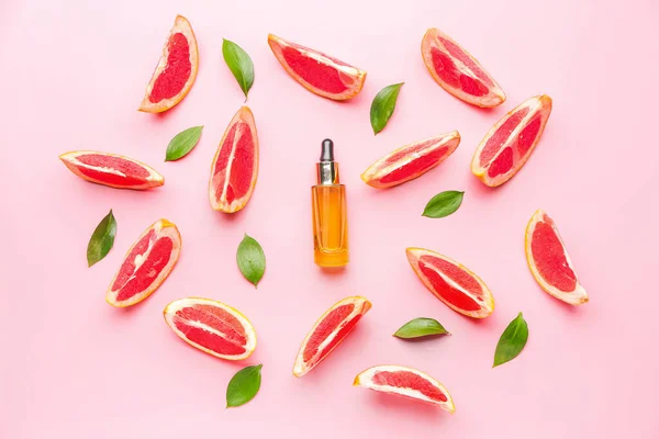 Пляшка ефірної олії та шматочків грейпфрута на кольоровому фоні — стокове фото