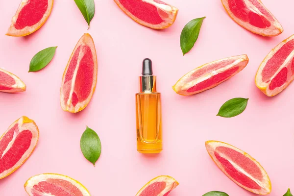 Bottle of essential oil and grapefruit slices on color background — Stock Photo, Image
