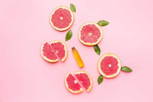 Bottle of essential oil and grapefruit slices on color background — Stock Photo, Image