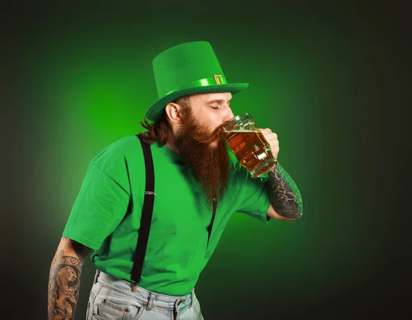 Hombre barbudo con un vaso de cerveza sobre fondo oscuro. Celebración del Día de San Patricio —  Fotos de Stock