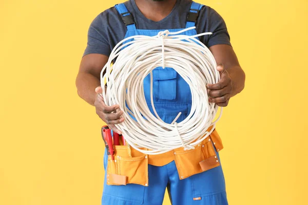 African-American electrician on color background