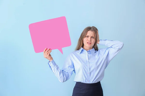 Confused young businesswoman with blank speech bubble on color background — Stock Photo, Image