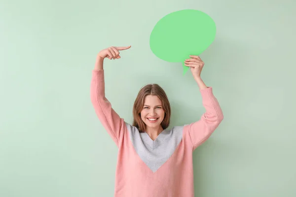 Young woman with blank speech bubble on color background — Stock Photo, Image