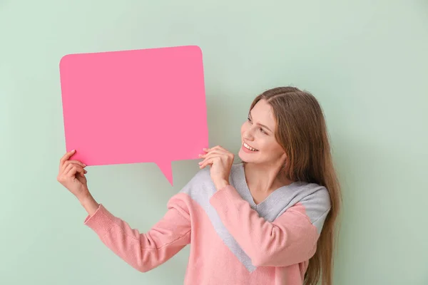 Young woman with blank speech bubble on color background — Stock Photo, Image