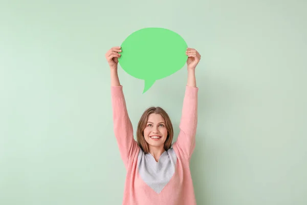 Young woman with blank speech bubble on color background — Stock Photo, Image