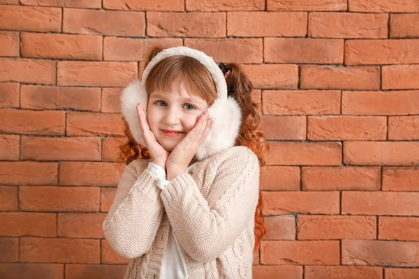 겨울 옷을 입고 벽돌 벽 근처에 있는 귀여운 소녀 — 스톡 사진