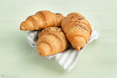 Beyaz masada lezzetli kruvasanlarla dolu bir tabak.