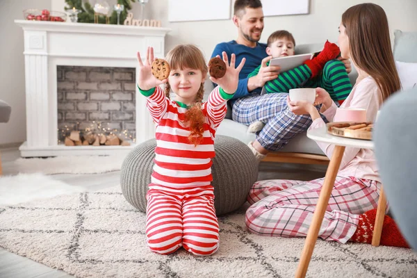 Liten flicka med kakor och familj hemma — Stockfoto