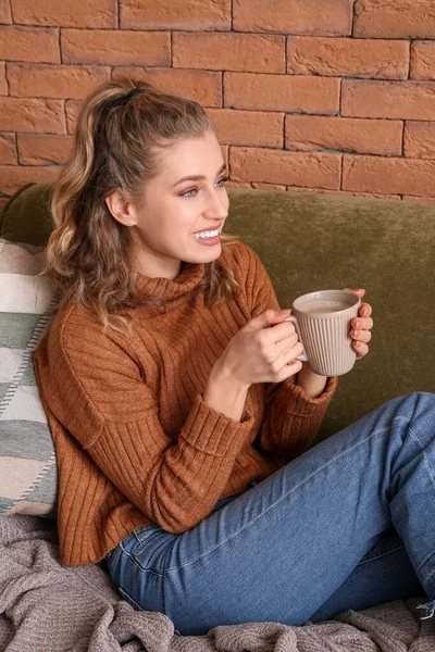 Glad ung kvinna i vinterkläder dricker varm choklad hemma — Stockfoto