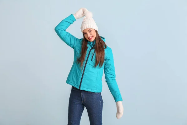 Happy young woman in winter clothes on color background — Stock Photo, Image