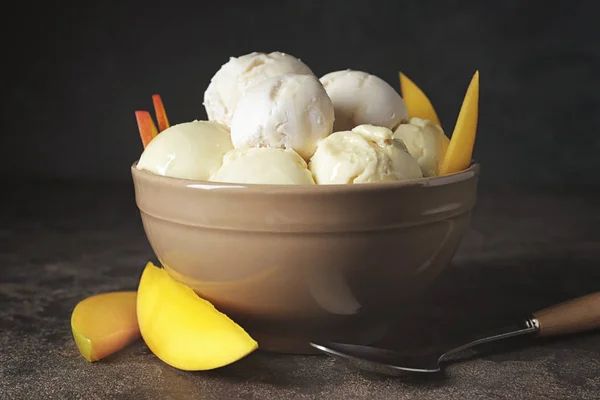 Tigela com saboroso sorvete e manga no fundo escuro — Fotografia de Stock