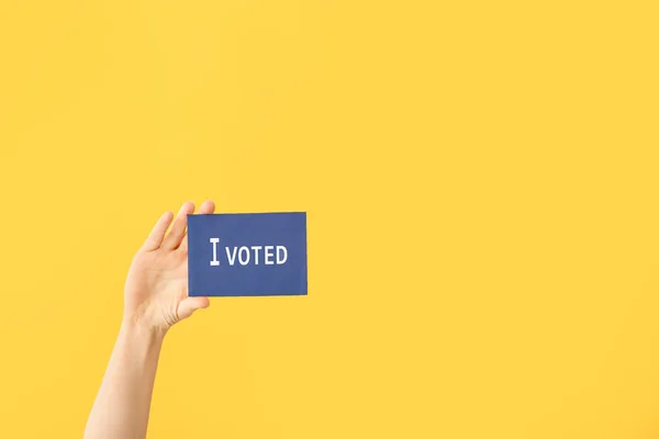 Hand holding paper with text I VOTED on color background — Stock Photo, Image