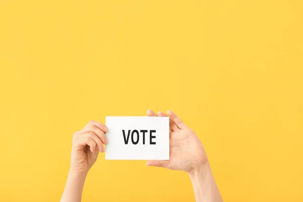 Hands holding paper with text VOTE on color background — Stock Photo, Image