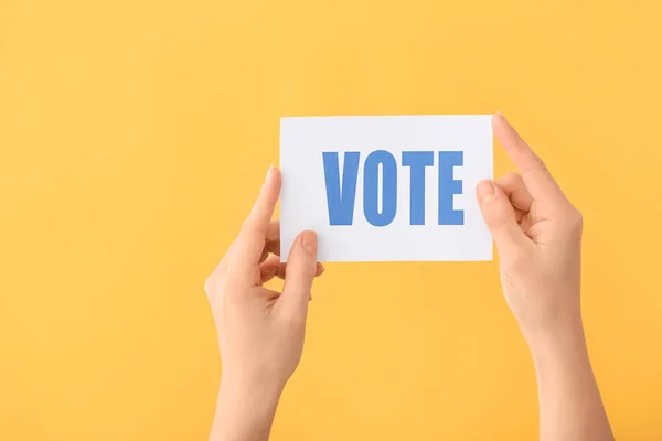Hands holding paper with text VOTE on color background — Stock Photo, Image