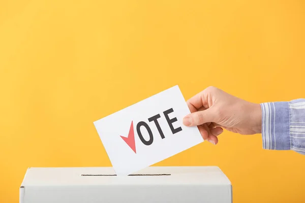 Röstande kvinna nära valurnan på färg bakgrund — Stockfoto