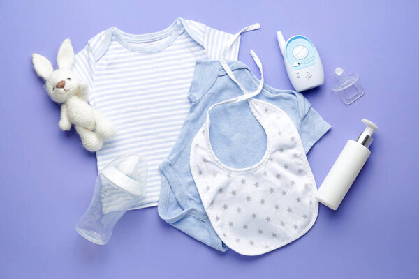 Baby monitor with clothes and accessories on color background