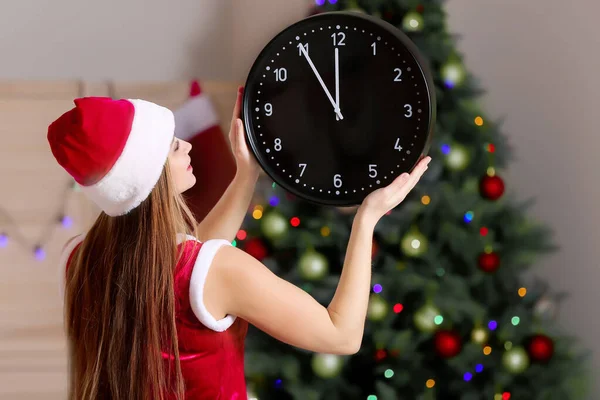 Giovane donna in costume da Babbo Natale e con orologio in camera. Conto alla rovescia di Natale — Foto Stock