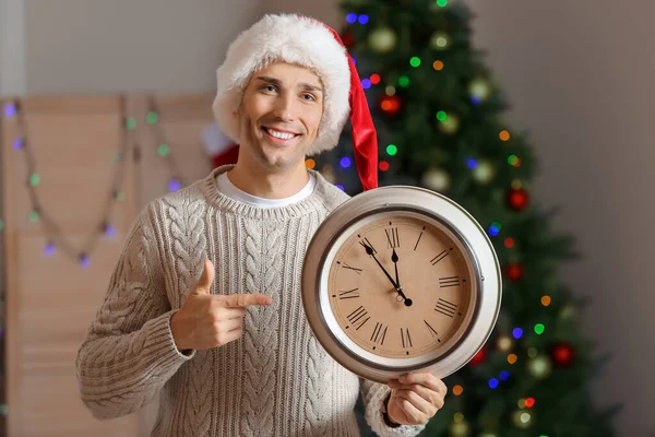 Ung man i tomte hatt och med klocka i rummet. Julnedräkning koncept — Stockfoto