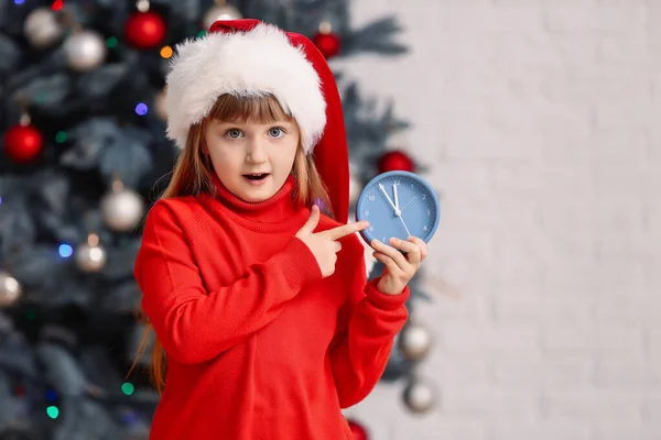 Κοριτσάκι με καπέλο και ξυπνητήρι στο σπίτι. Χριστούγεννα αντίστροφη μέτρηση έννοια — Φωτογραφία Αρχείου