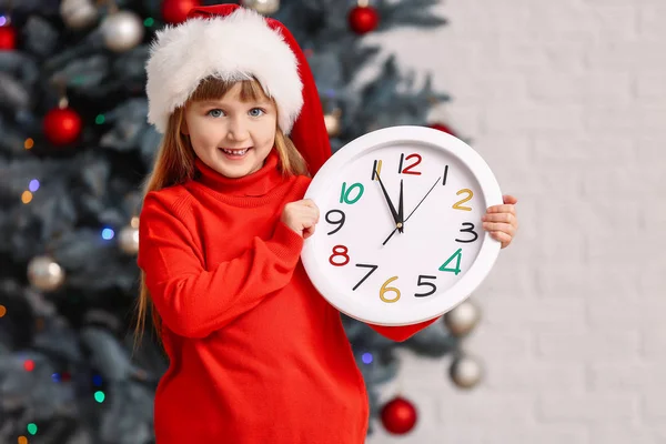 Κοριτσάκι με καπέλο και ρολόι στο σπίτι. Χριστούγεννα αντίστροφη μέτρηση έννοια — Φωτογραφία Αρχείου