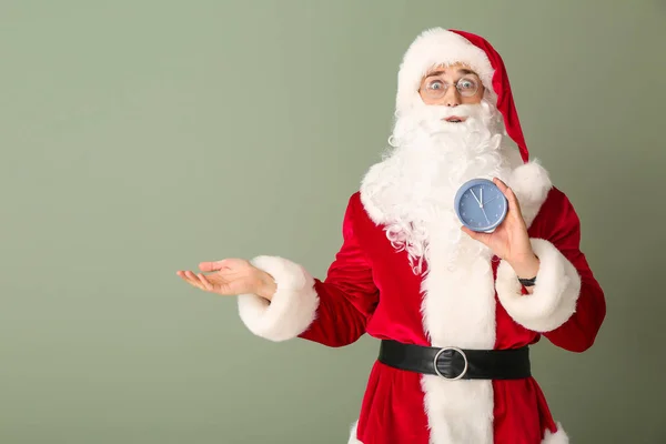 Surpreendido Papai Noel com despertador no fundo da cor. Conceito de contagem regressiva de Natal — Fotografia de Stock