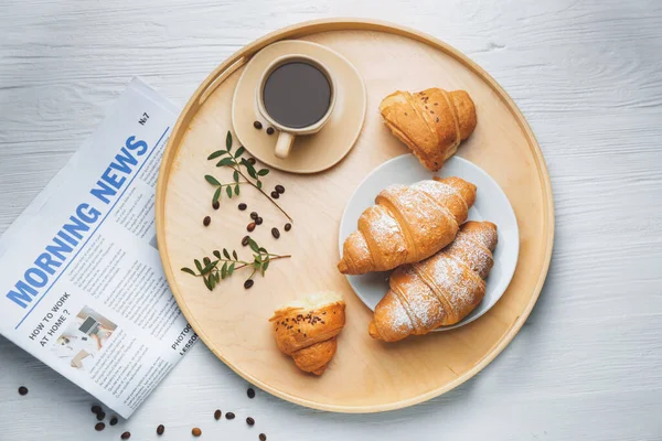 Bandeja con sabrosos croissants y taza de café sobre mesa blanca — Foto de Stock