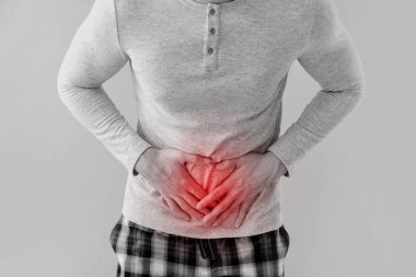 Hafif arka planda karın ağrısı çeken genç bir adam.