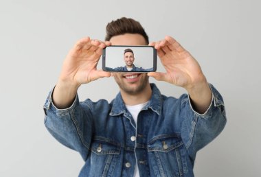 Yakışıklı adam arka planda selfie çekiyor.