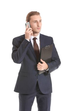 Erkek emlakçı beyaz arka planda cep telefonuyla konuşuyor.