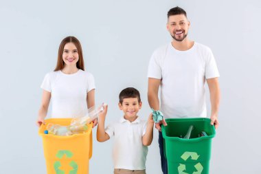 Arka planda çöp konteynırları olan bir aile. Geri dönüşüm kavramı