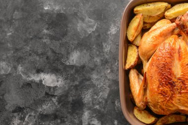 Koyu arkaplanda fırında tavuk ve patates var.