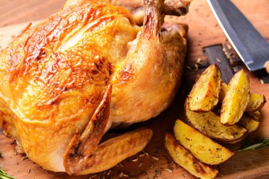 Baked chicken and potato on wooden board, closeup