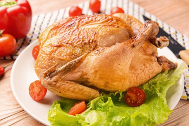 Plate with baked chicken on wooden table