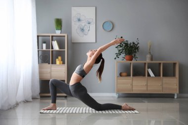 Güzel genç bayan evde yoga yapıyor.