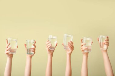 Renkli arka planda su bardakları olan kadın elleri