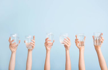 Renkli arka planda su bardakları olan kadın elleri