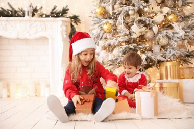 Küçük çocuklar evde Noel hediyelerini açıyor.