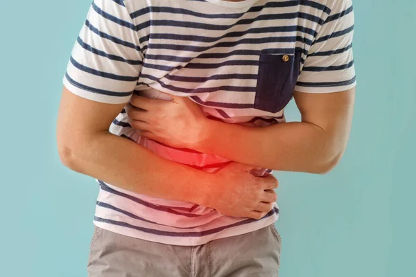 Hombre joven que sufre de dolor abdominal en el fondo de color —  Fotos de Stock
