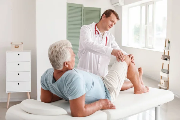 Médico examinando hombre maduro con dolor articular en clínica —  Fotos de Stock