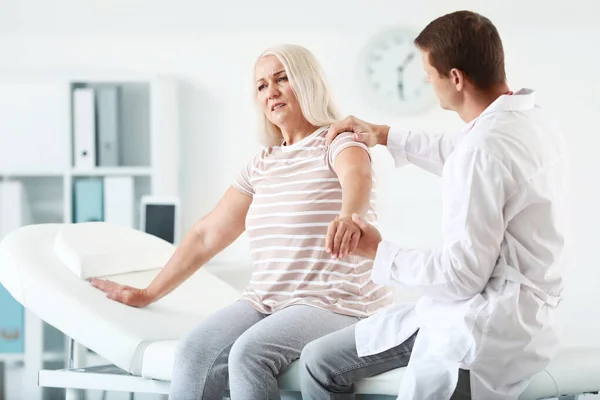 Doctor examining mature woman with joint pain in clinic — Stock Photo, Image